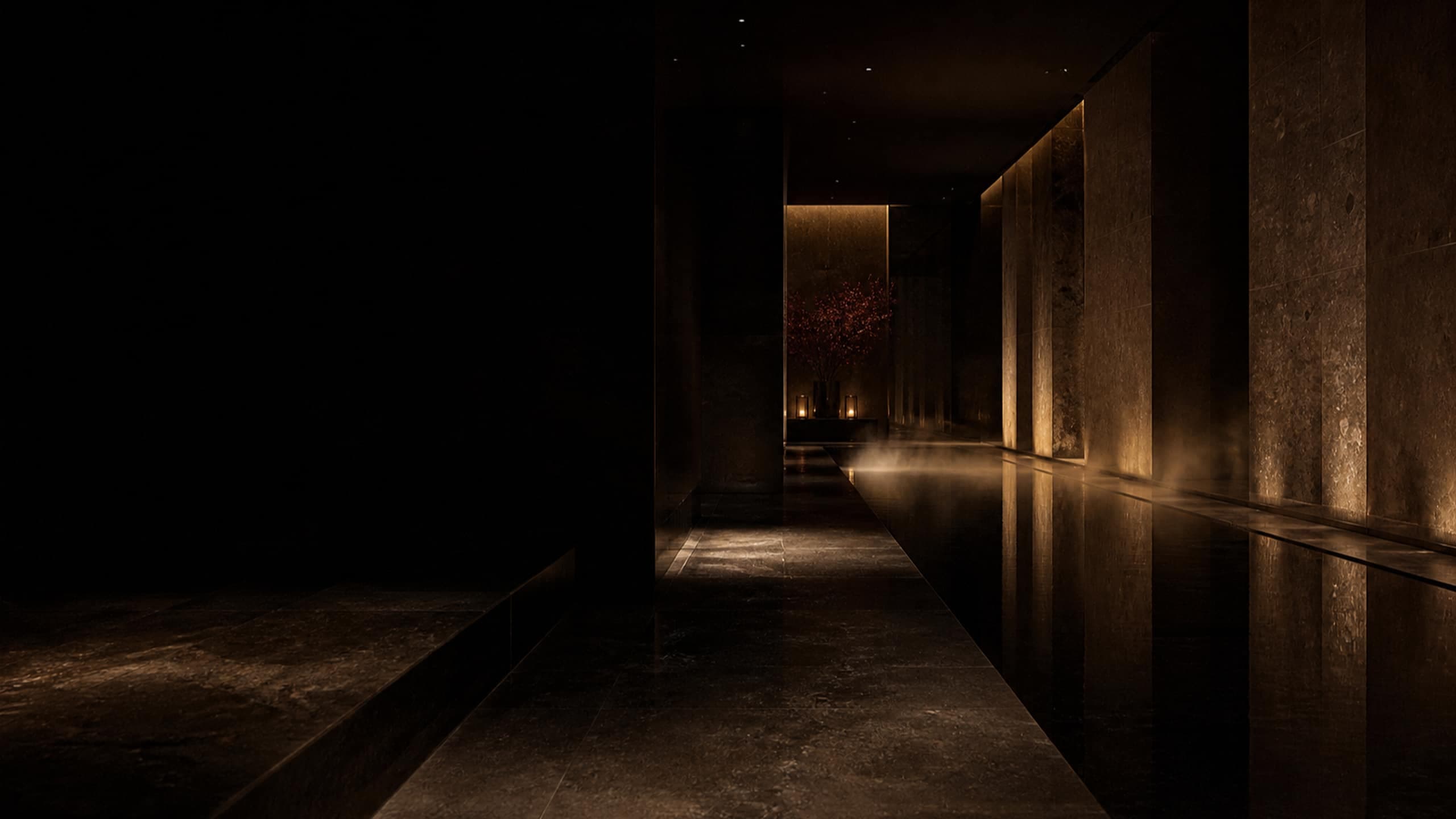 A dark stone corridor beside a still reflecting pool, lit by warm low light